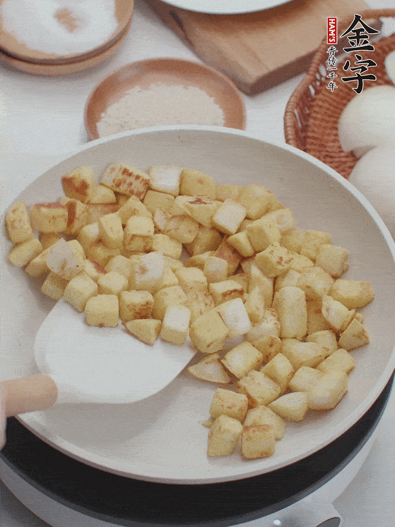 起鍋熱油，倒入饅頭丁，小火煎至蛋液凝固定型再翻面，饅頭丁部煎至金黃時(shí)盛起待用。